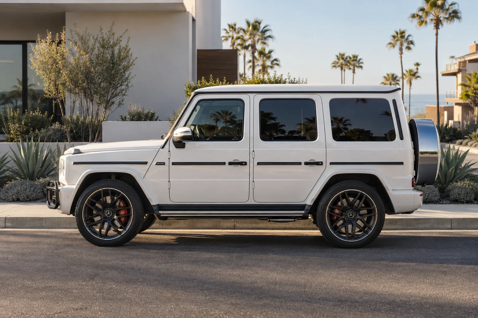 A white Mercedes G-Class with dark tinted windows parked on a sunny street