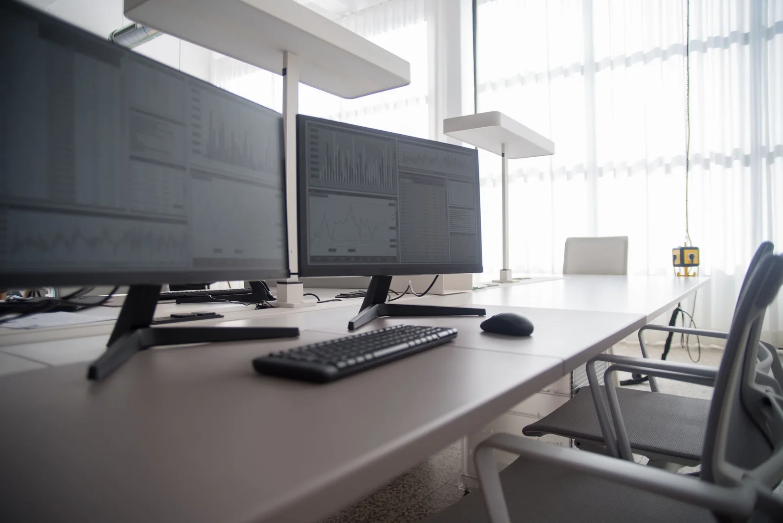 Computer screens on desks beside a bright window