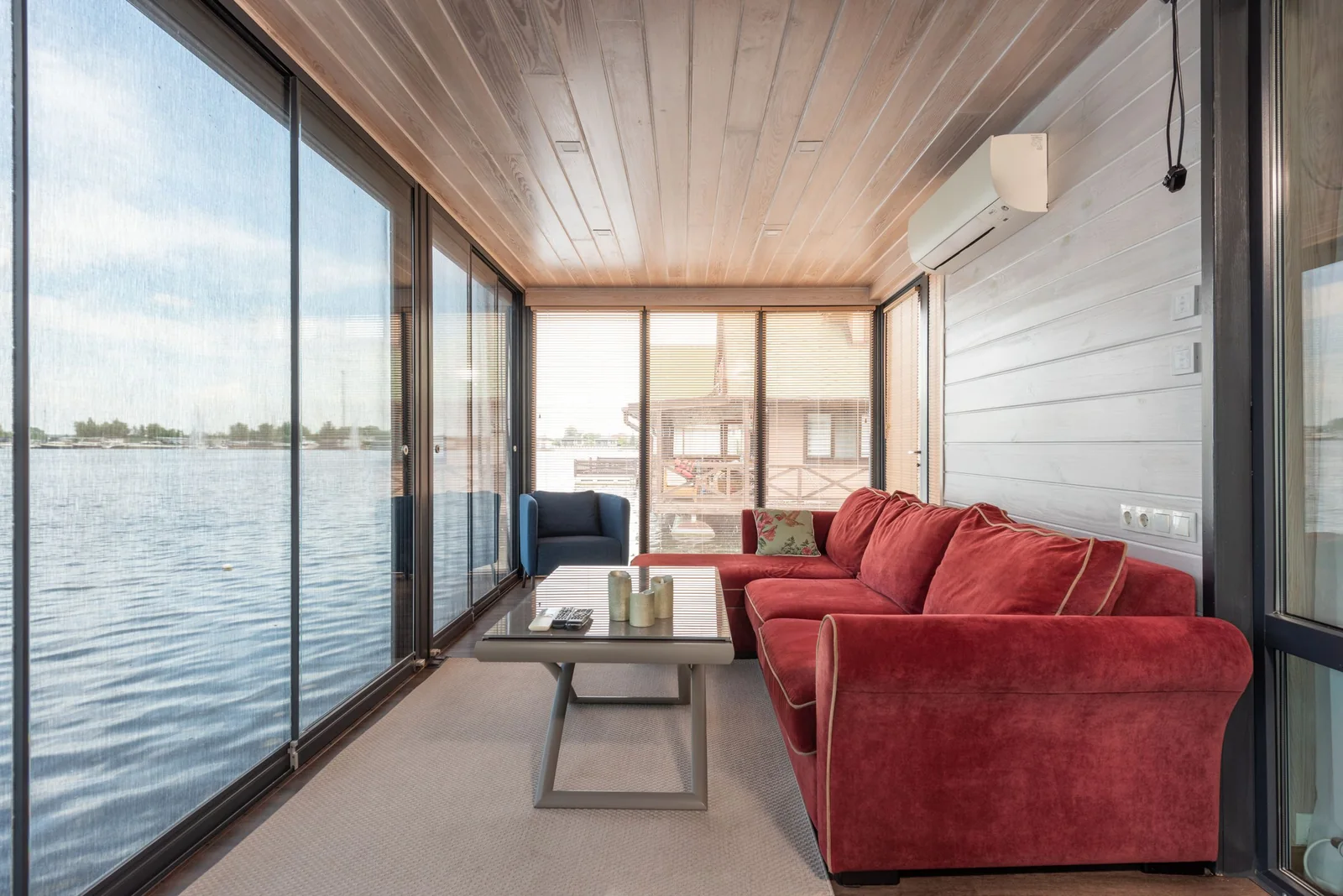 A sunny room walled in glass, looking out over the water